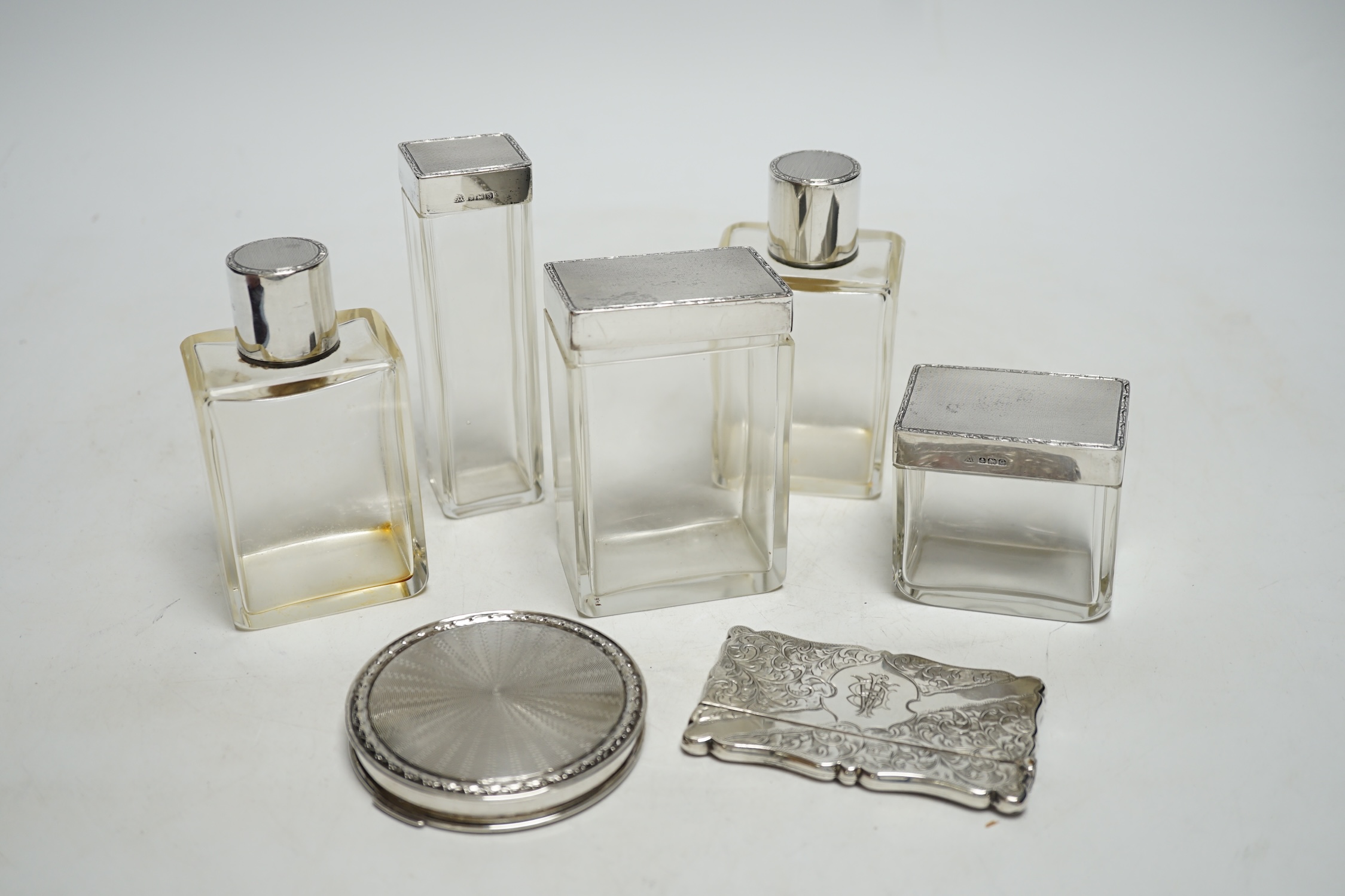 Five assorted silver topped glass toilet jars, a silver compact and an Edwardian engraved silver card case, Birmingham, 1902, 83mm.